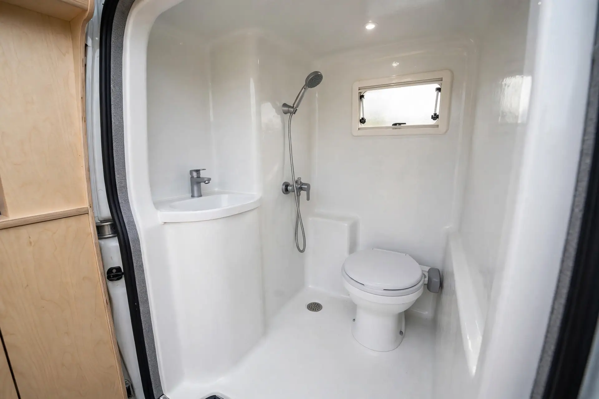 Compact all-in-one fiberglass wet bath inside a camper van with shower, toilet and sink